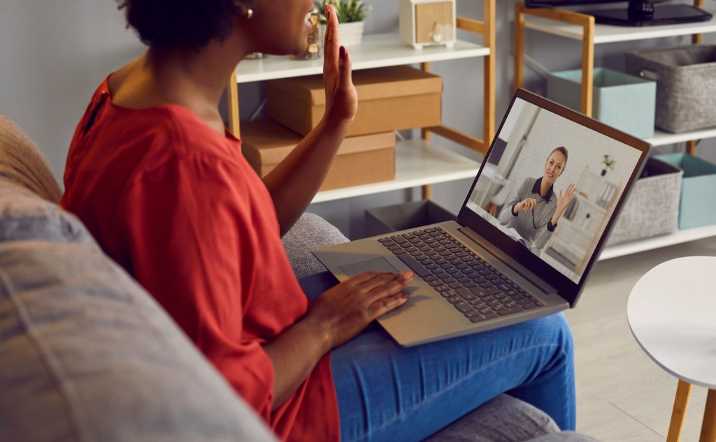 Woman waving hello to doctor on telehealth program.