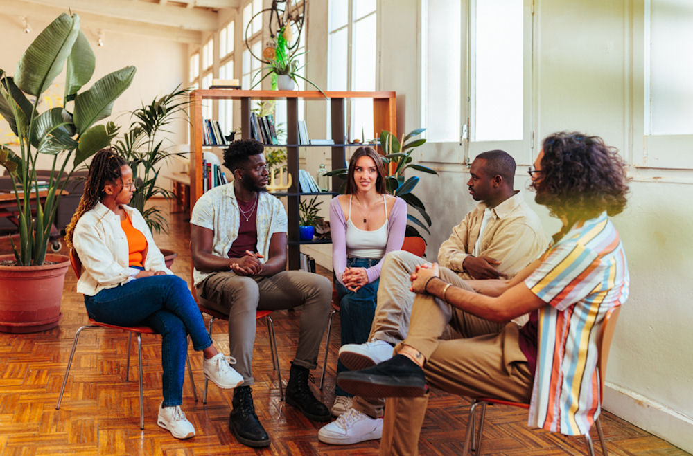 Diverse group of young adults talking openly in a bright group session