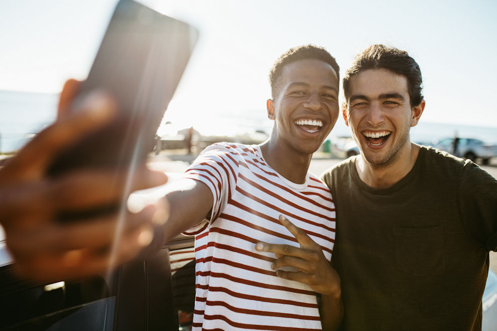 Two young men taking a cheerful selfie by the water